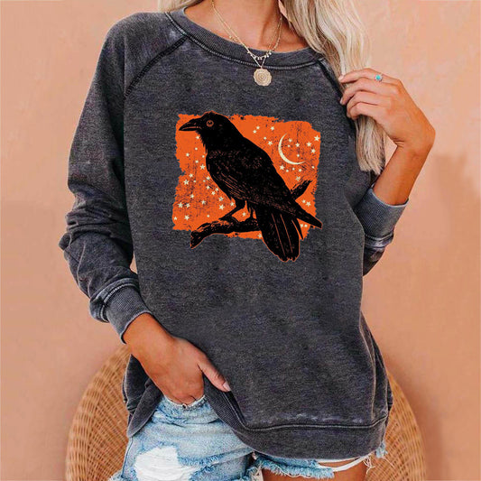 Person wearing a dark gray sweatshirt with a black crow design on an orange background.