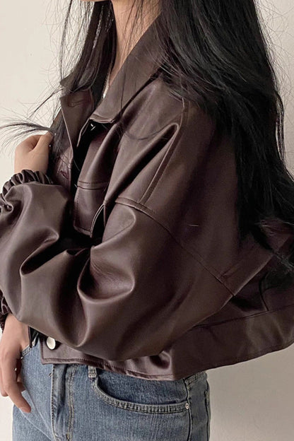 Person wearing a brown leather jacket and blue jeans against a neutral background