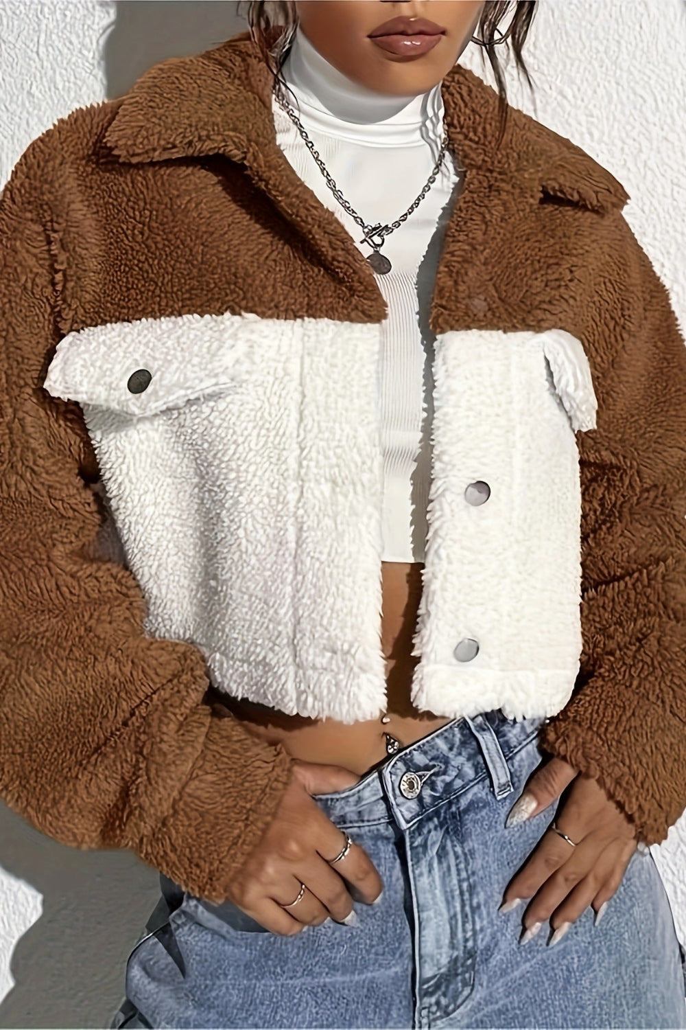 Brown and white sherpa jacket worn by a person against a white background