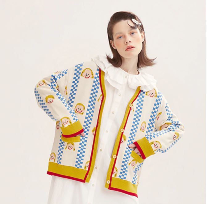 Woman wearing a colorful patterned cardigan with a plain background