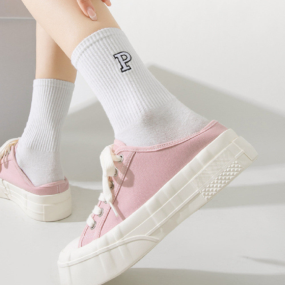 Pink sneakers worn with white socks on a light background