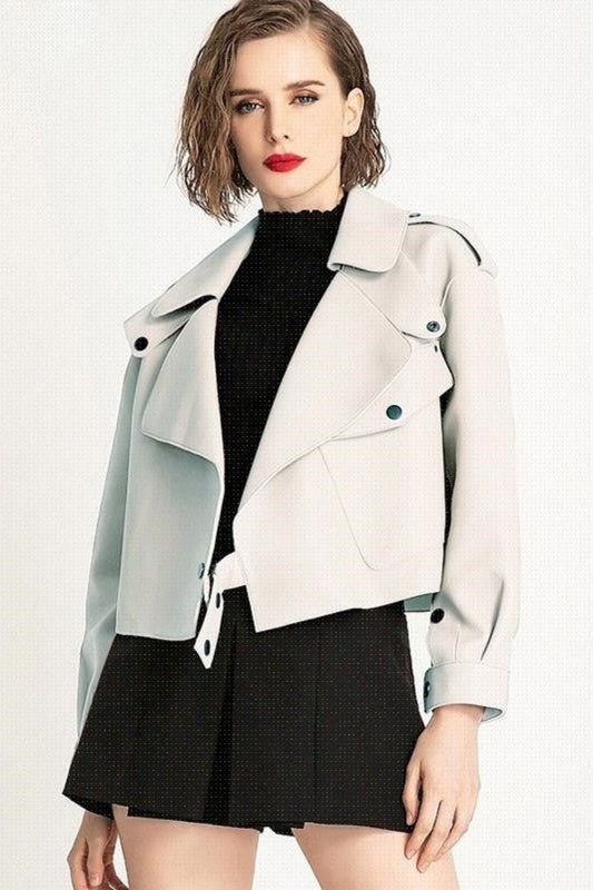 Woman wearing a light gray jacket over a black top and skirt on a white background