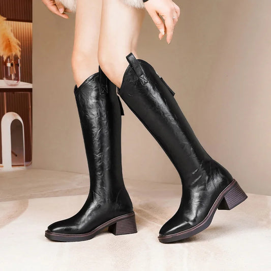 Black knee-high boots worn by a person on a neutral background