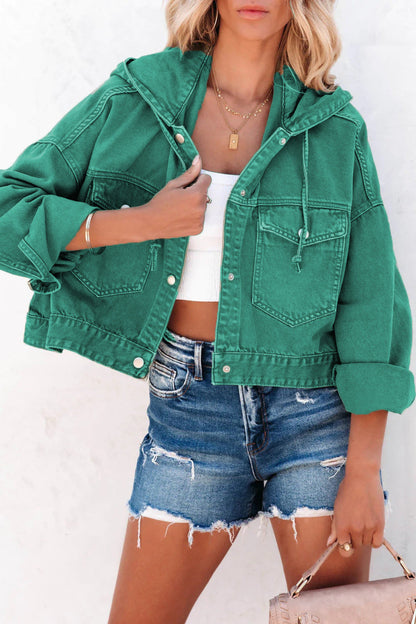Person wearing a green denim jacket and denim shorts with a white background