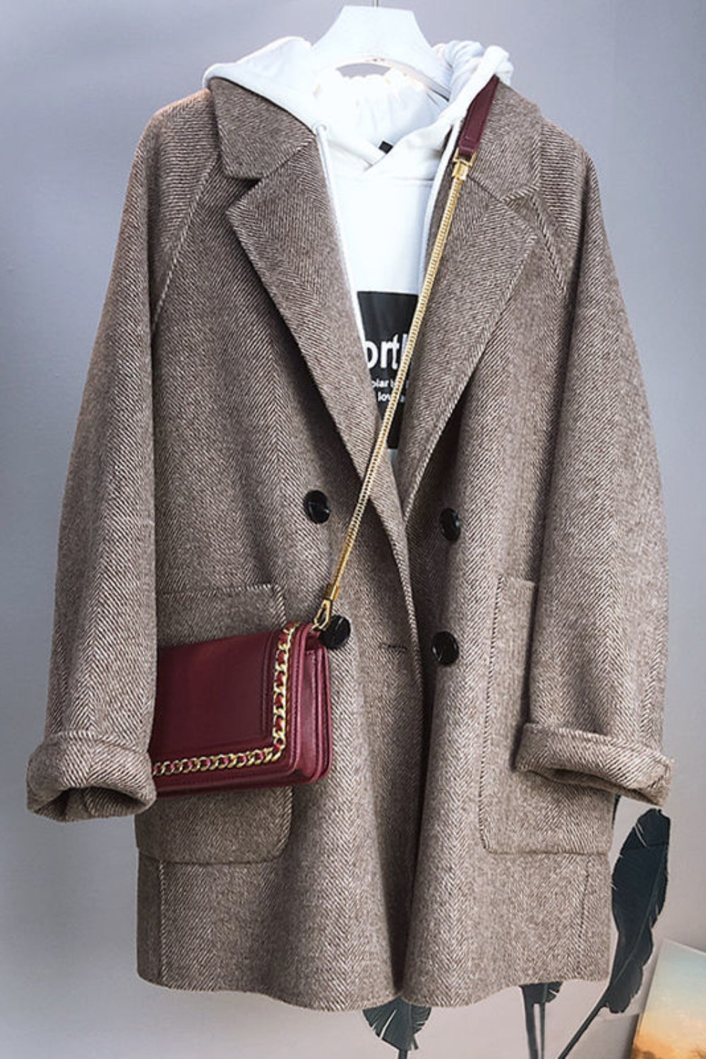 Brown coat with a red handbag on a mannequin against a gray background