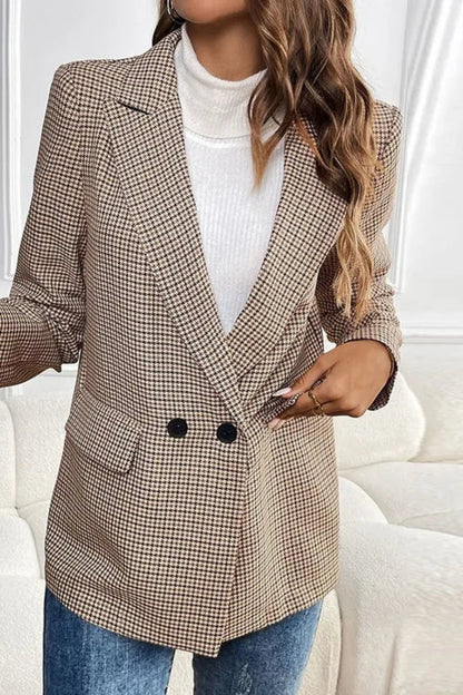 Woman wearing a plaid blazer over a white top in a minimalistic room.