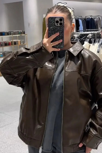 Person wearing a brown leather jacket in a clothing store.