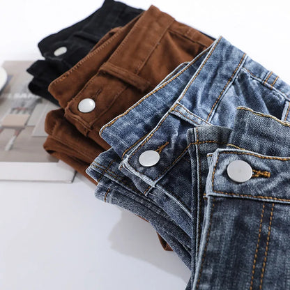 Stack of folded jeans in various colors on a white surface