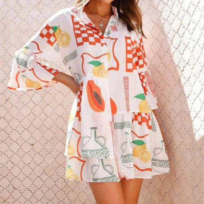 Woman wearing a colorful dress with fruit and geometric patterns against a textured wall.