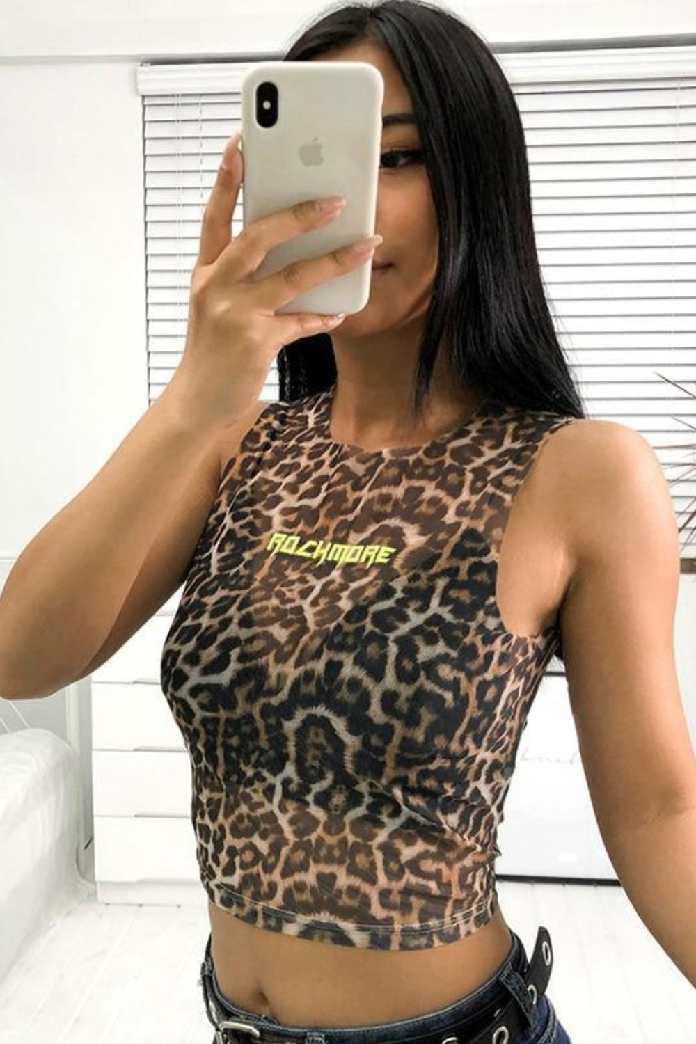 Person wearing a leopard print top with 'Balmain' branding, taking a mirror selfie.