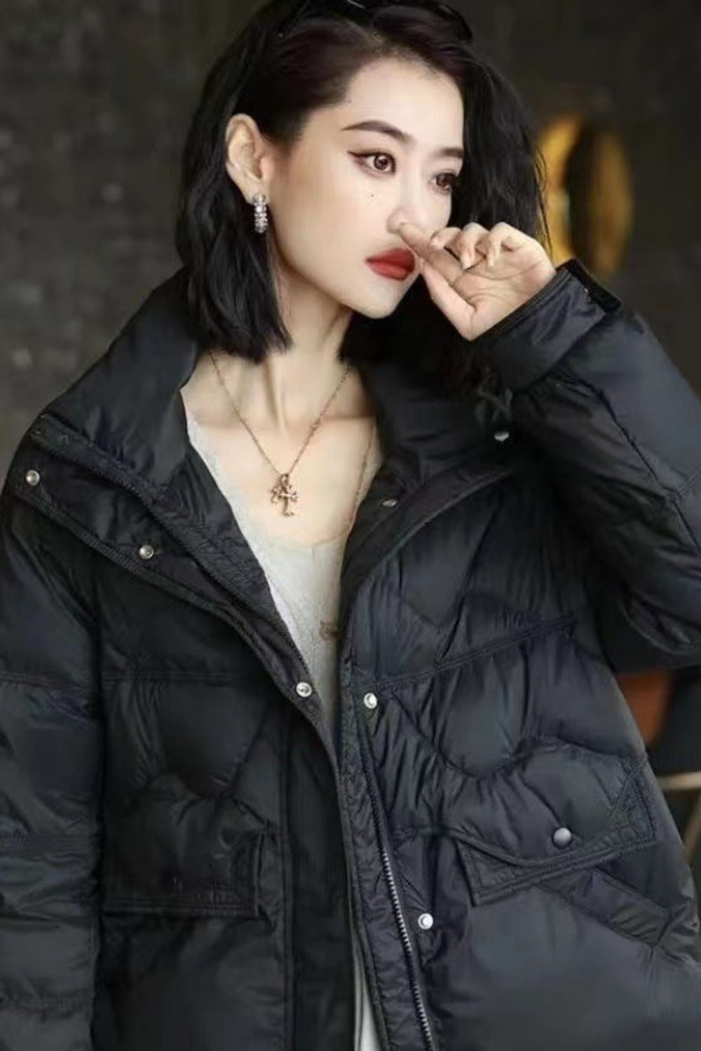 Woman wearing a black puffer jacket indoors with blurred background