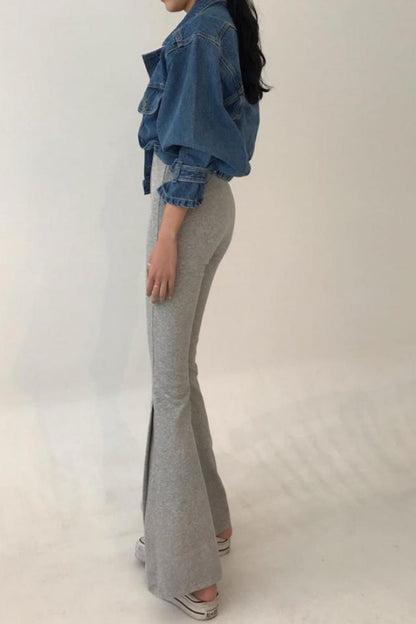 Person wearing a blue denim jacket and gray flared pants on a white background