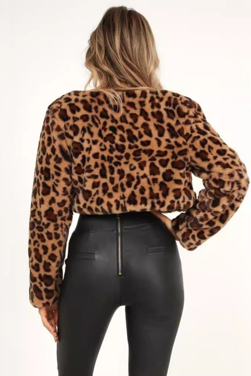 Person wearing a leopard print top and black pants on a white background
