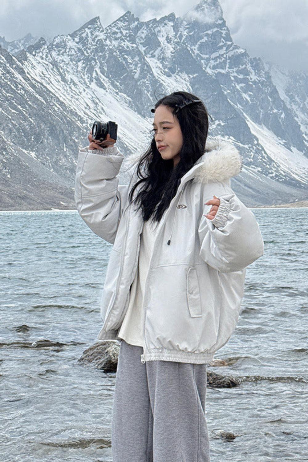 Person taking a photo of a scenic lake with mountains in the background