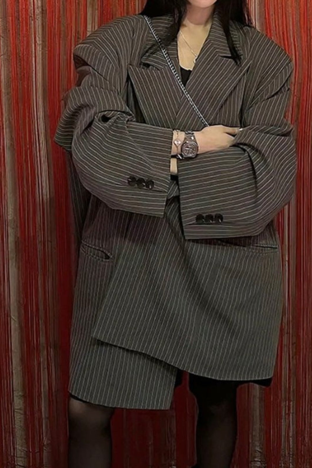 Person wearing a pinstripe coat in front of a red curtain
