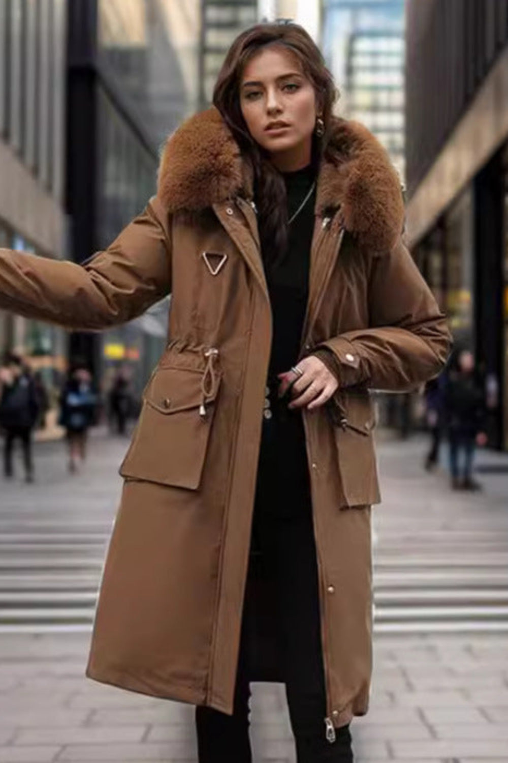 Woman wearing a brown coat with fur hood on a city street
