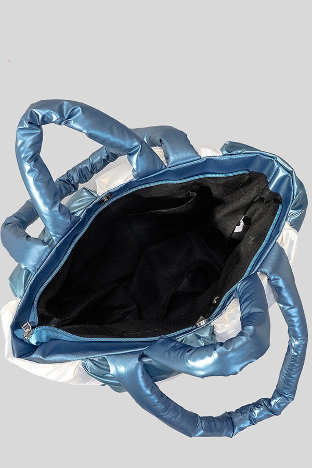 Blue metallic handbag with unique handle design on a light gray background