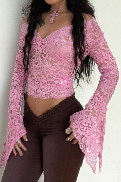 Person wearing a pink lace top and brown pants against a white background