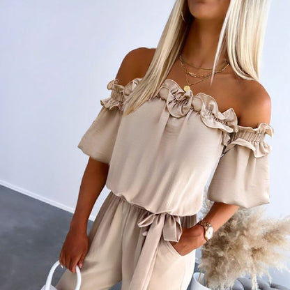 Woman wearing a beige off-shoulder top and pants with ruffled details.