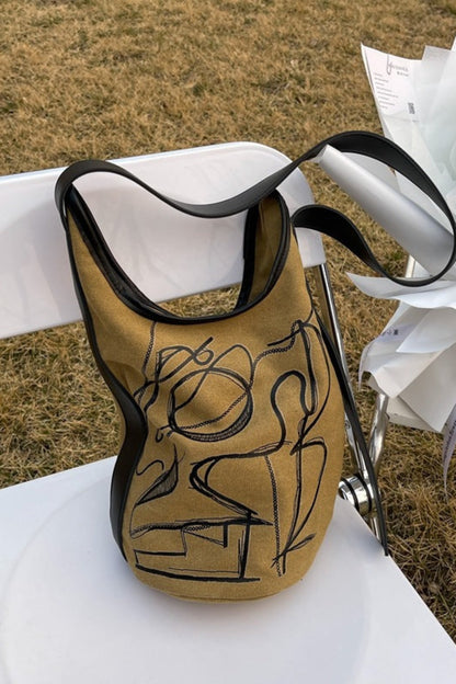 Gold and black bag with artistic design on a white chair outdoors