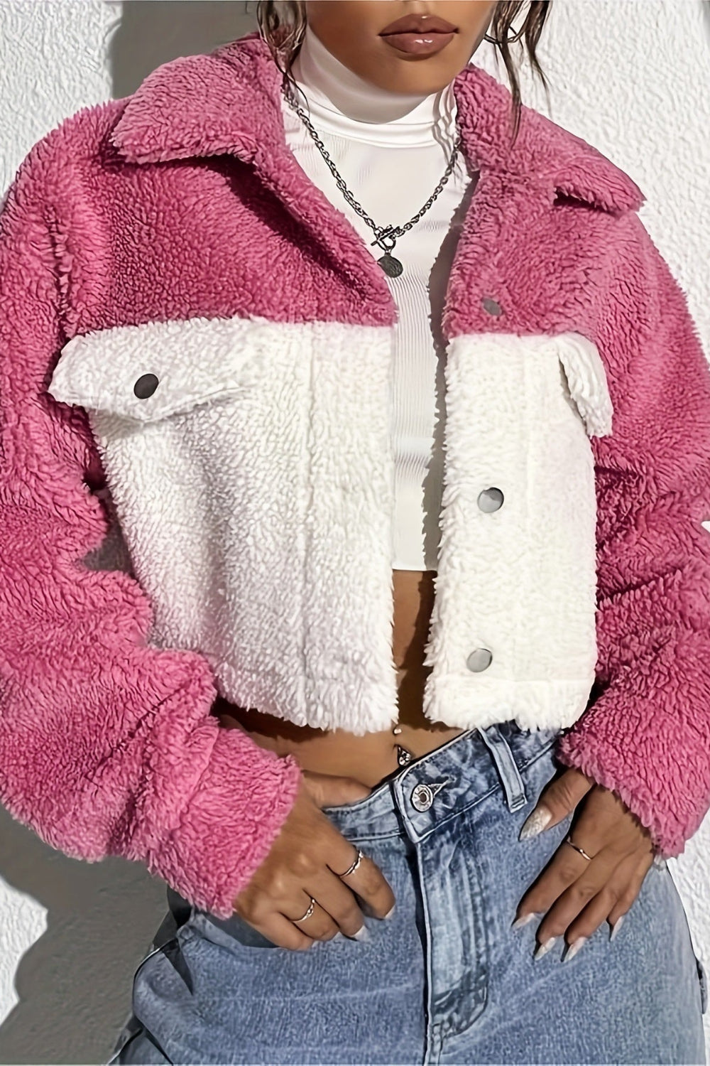 Person wearing a pink and white fleece jacket with blue jeans against a white background