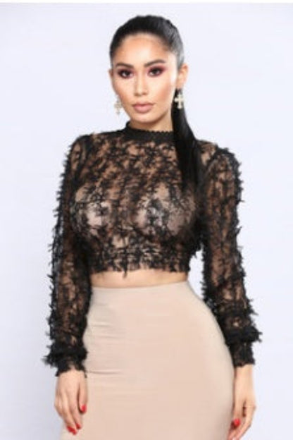 Woman wearing a black lace top and beige skirt against a light gray background