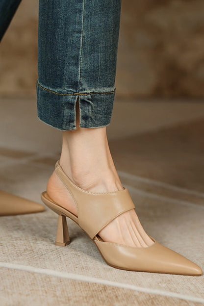 Beige high-heeled shoes worn with rolled-up jeans on a neutral background