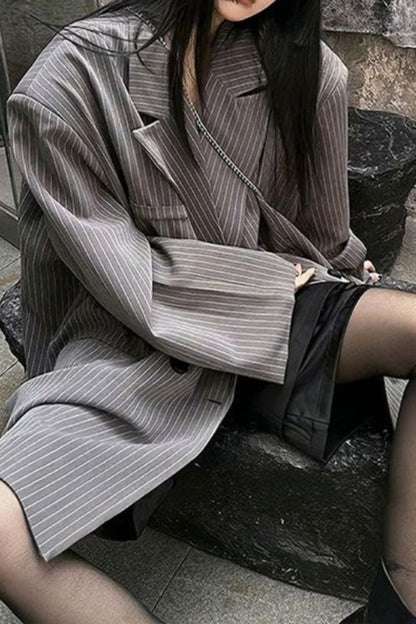 Person wearing a gray pinstripe coat sitting on stone steps.