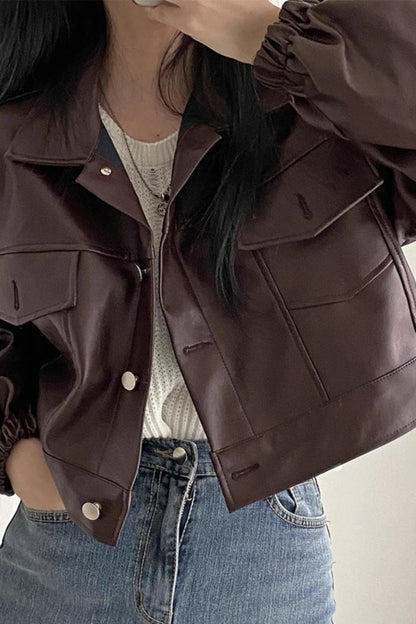 Person wearing a brown jacket and blue jeans against a plain background