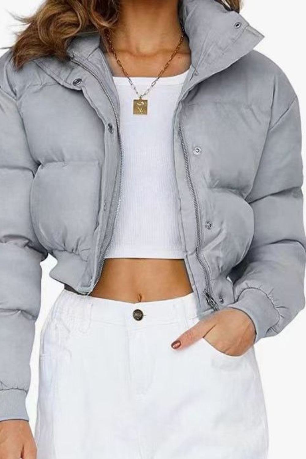 Person wearing a gray puffer jacket over a white top and pants on a white background