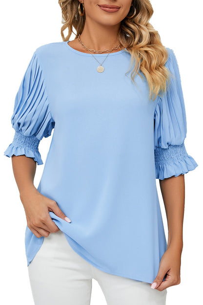 Woman wearing a light blue blouse with puffed sleeves on a white background