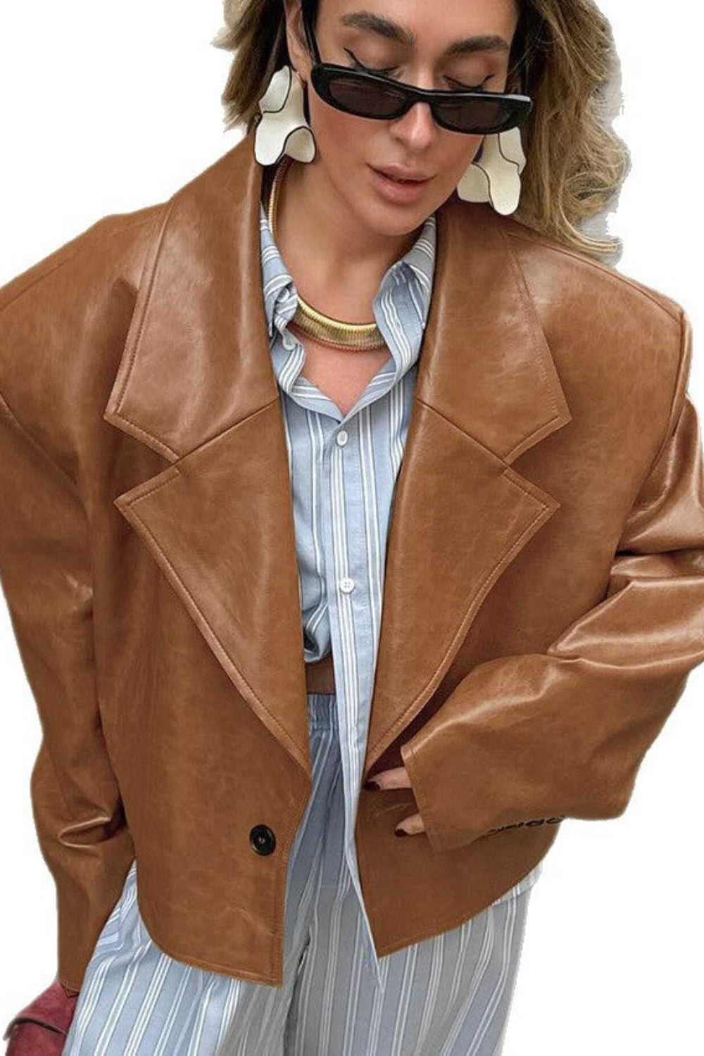 Person wearing a brown leather jacket over a striped shirt on a white background