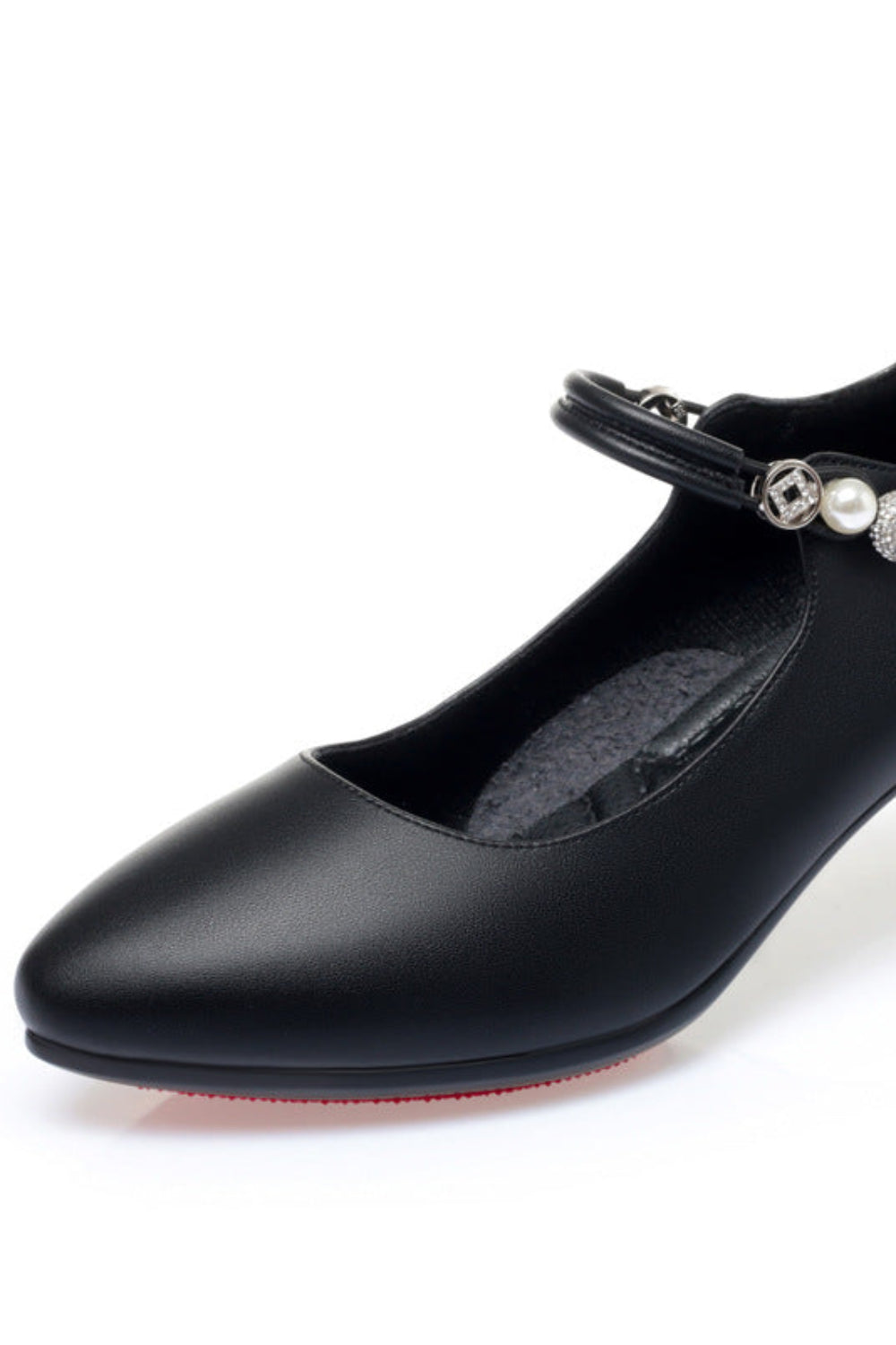 Black shoe with a strap and pearl embellishments on a white background