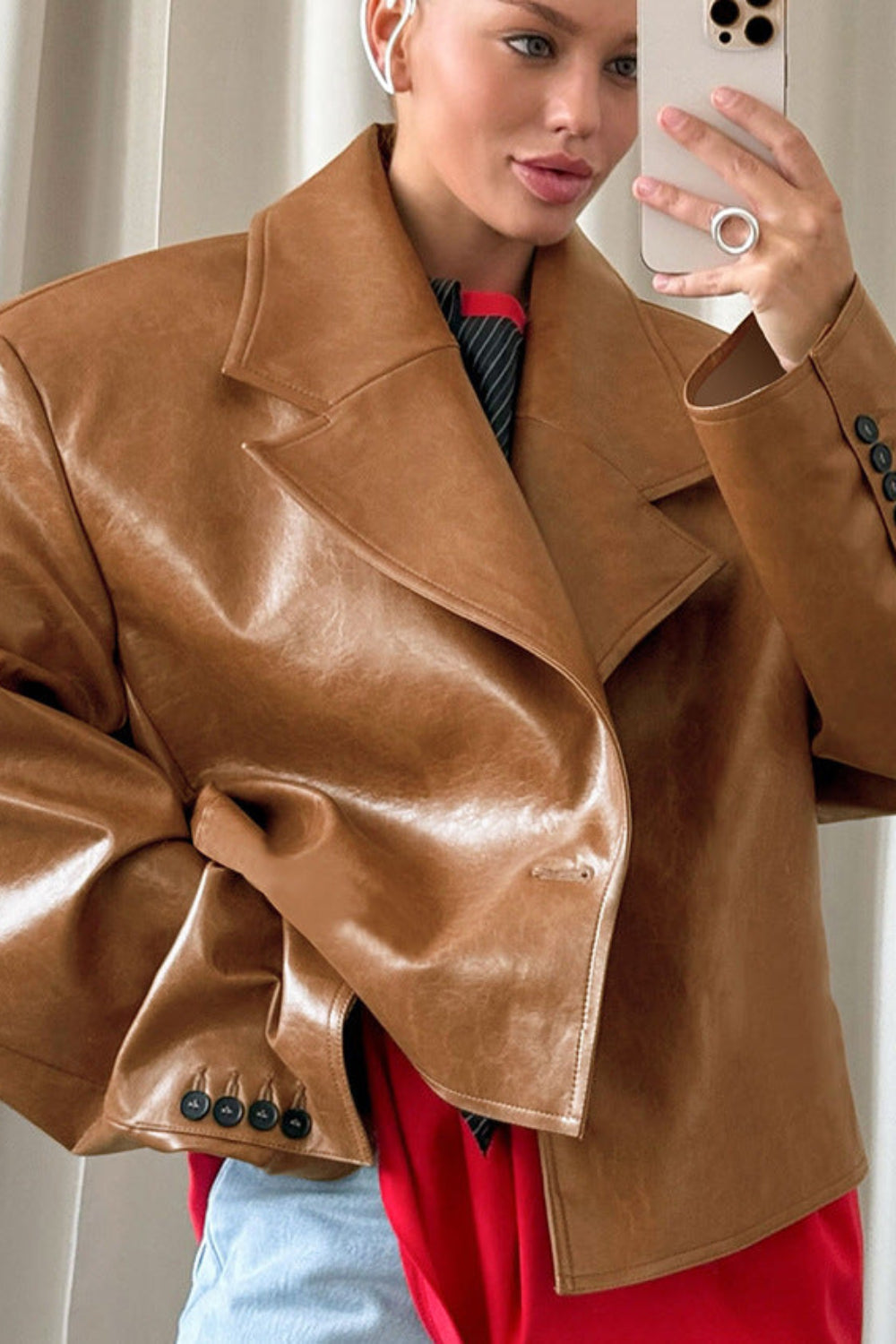 Woman wearing a brown leather jacket taking a selfie.