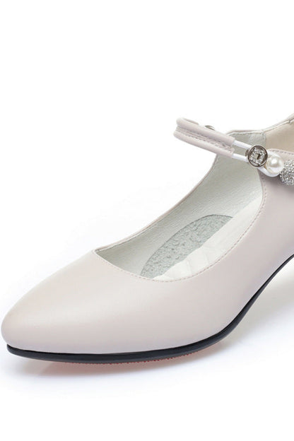 White shoe with a pearl embellishment on a white background