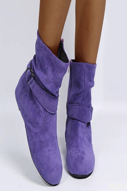 Purple suede boots with buckles on a white background