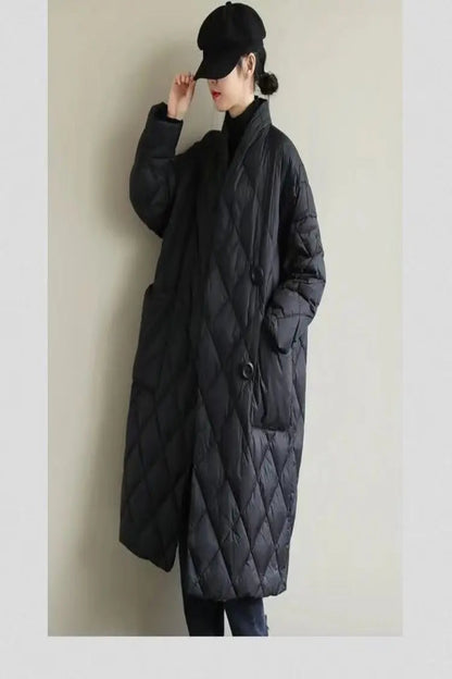 Person wearing a long black quilted coat against a plain background
