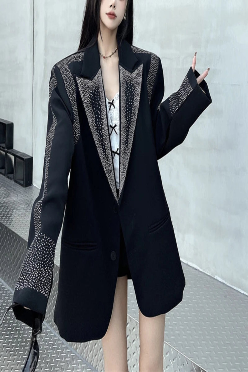 Person wearing a black blazer with decorative elements in an indoor setting