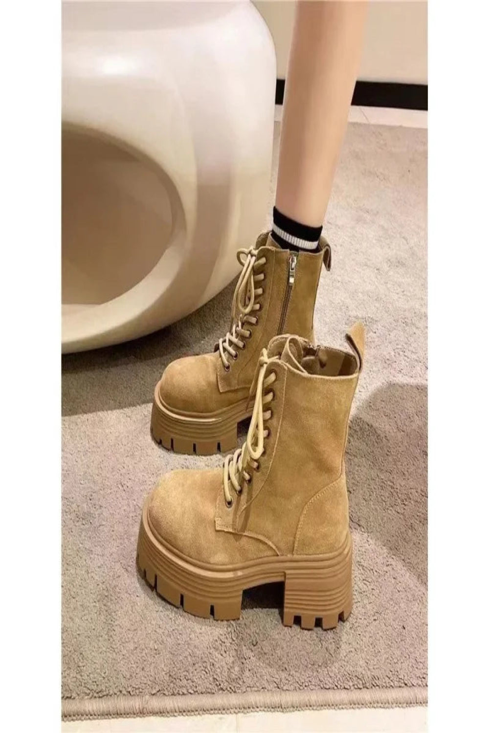 Tan combat boots worn indoors on a neutral background