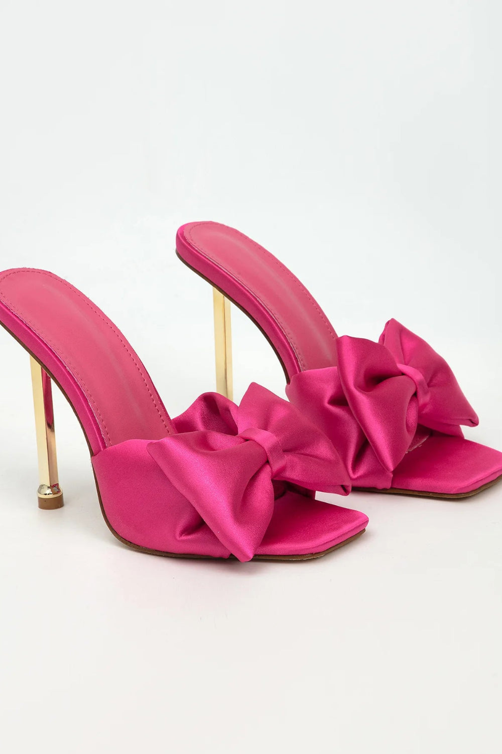 Pink high-heeled shoes with large bows on a white background