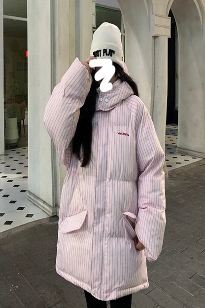 Person wearing a light pink puffer jacket with a brand logo, standing in an outdoor setting.