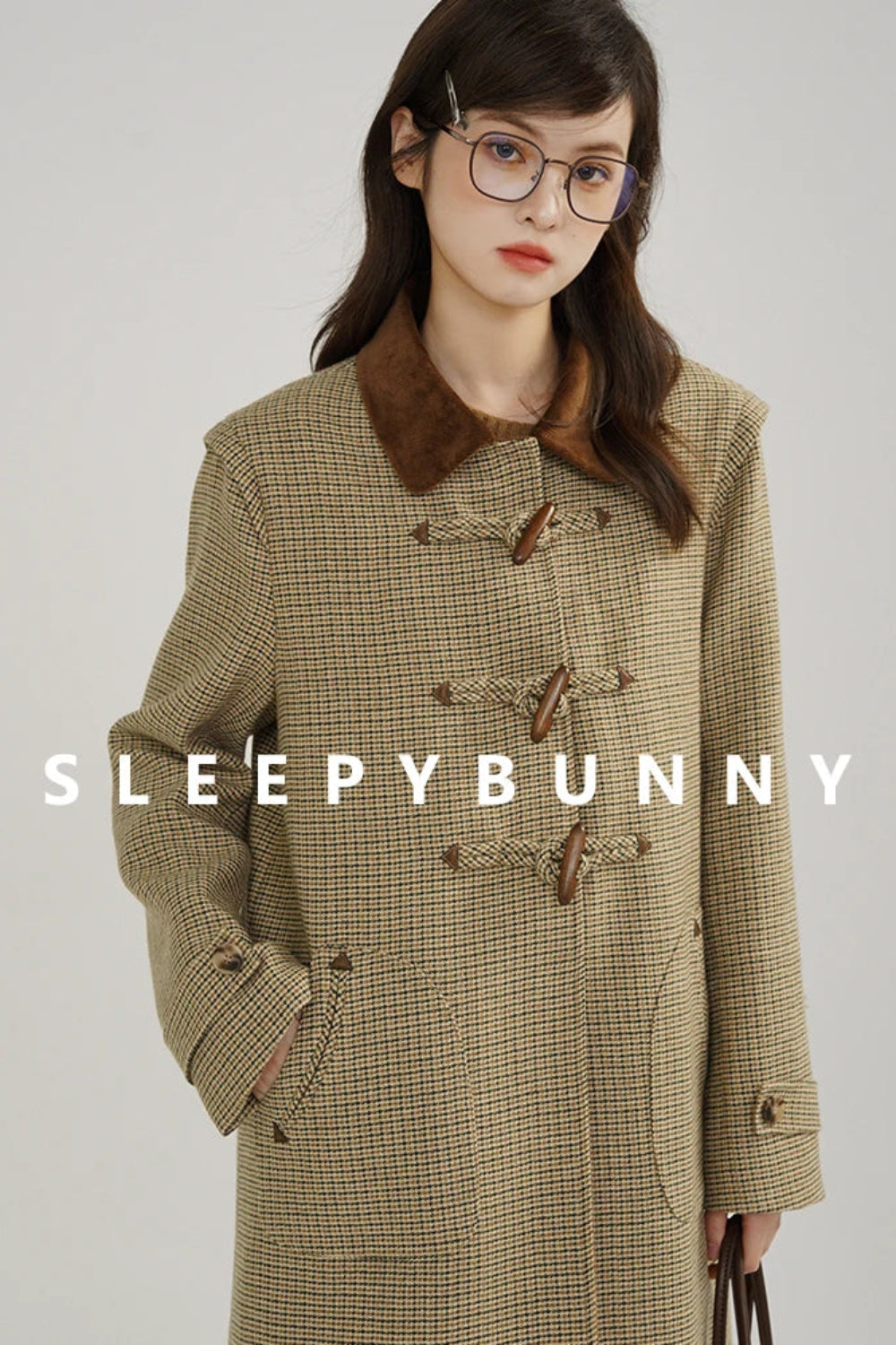 Woman wearing a plaid coat with 'Sleepy Bunny' branding on a gray background