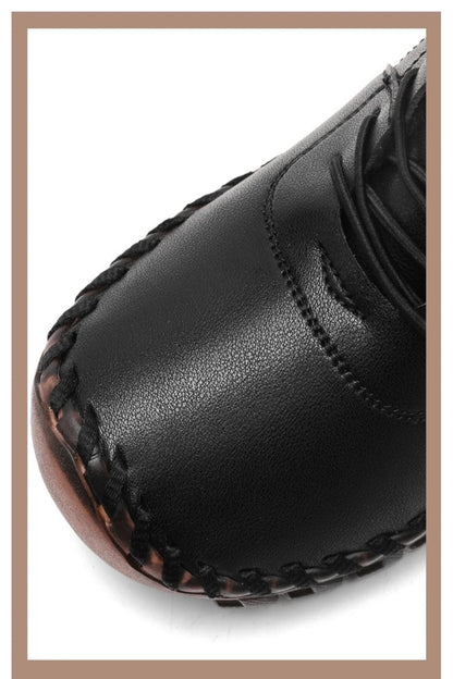 Close-up of a black leather shoe with brown stitching on a white background