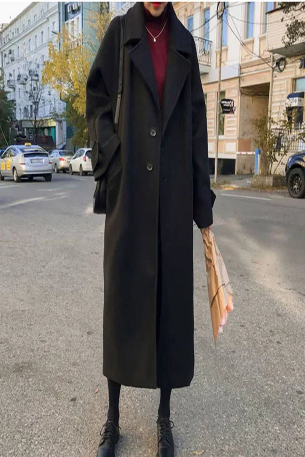 Person wearing a long black coat on a city street