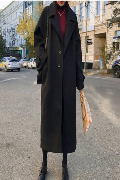 Person wearing a long black coat on a city street