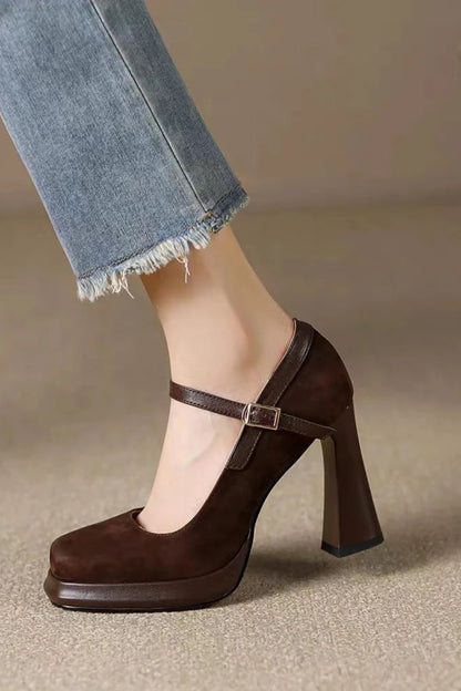Brown high-heeled shoe worn with light blue jeans on a neutral background