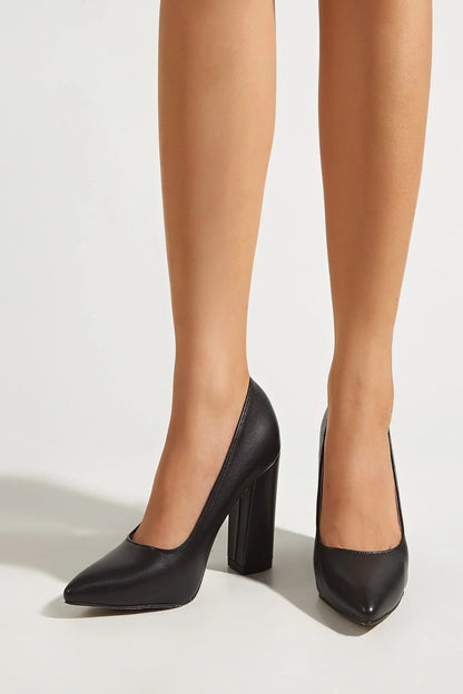 Black high-heeled shoes worn with beige tights on a white background