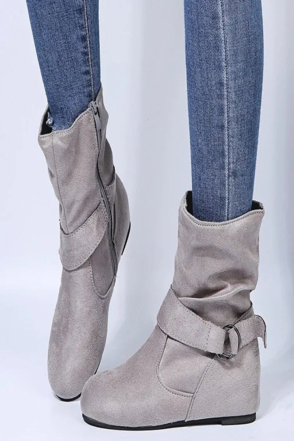 Gray ankle boots worn with blue jeans on a light gray background