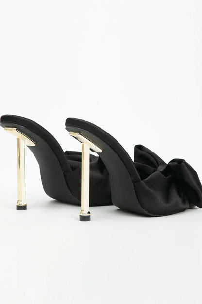 Black high-heeled shoes with gold accents on a white background