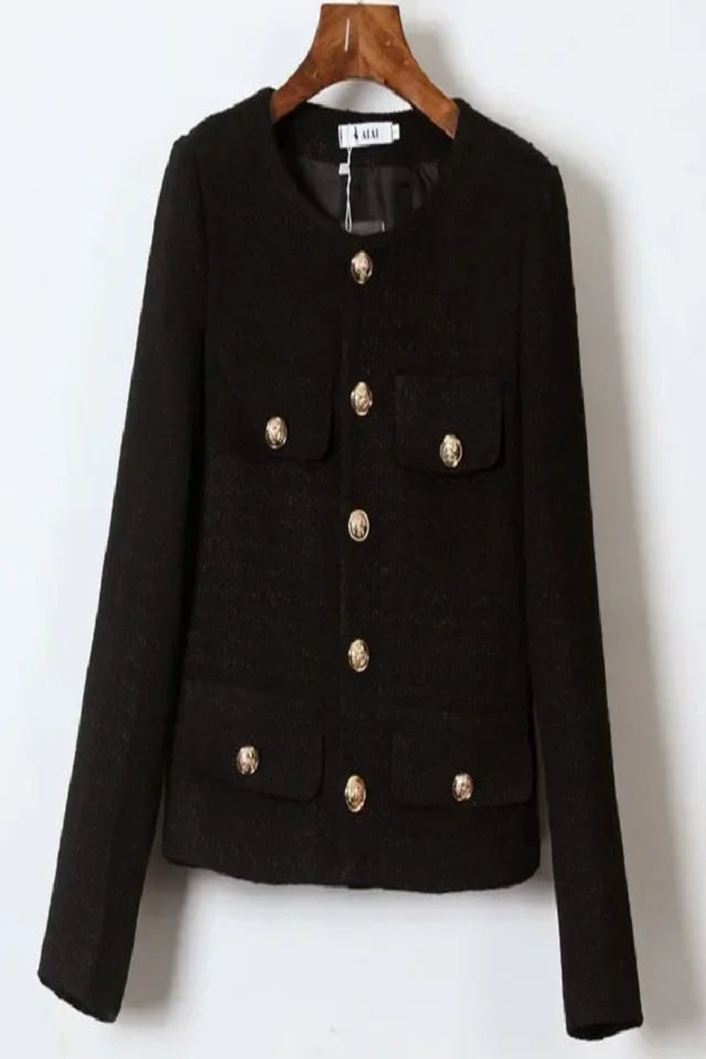 Black jacket with gold buttons on a wooden hanger against a white background